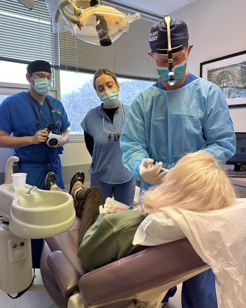 Dental implant instructor demonstrating a dental implant procedure to dentists during a continuing education course.