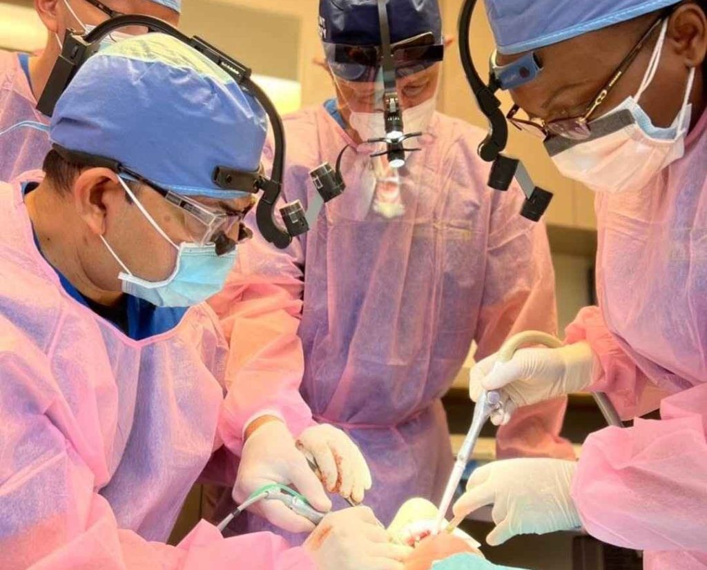 Oral surgeons performing a dental implant procedure during advanced surgical training