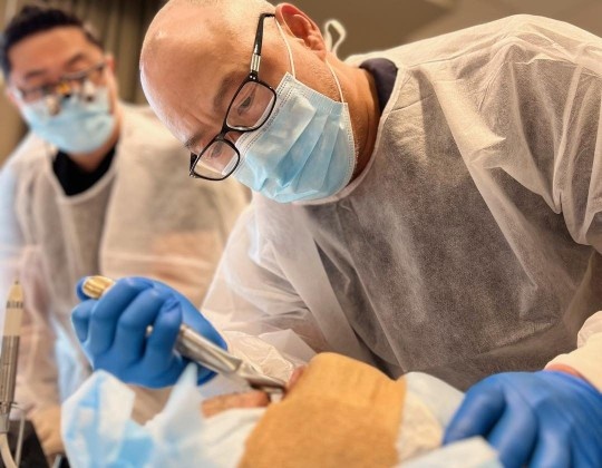Dentist performing dental implant placement during hands-on continuing education course. How Implant CE Courses Improve Patient Outcomes
